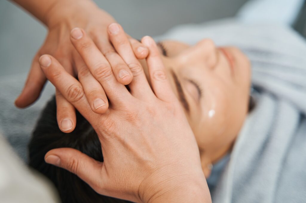 Dark-haired lady lying with closed eyes during a scalp massage